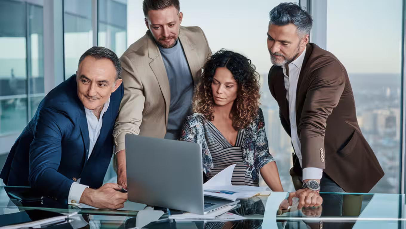 Fractional CCO consulting with three business professionals, all looking at a laptop screen during a meeting.